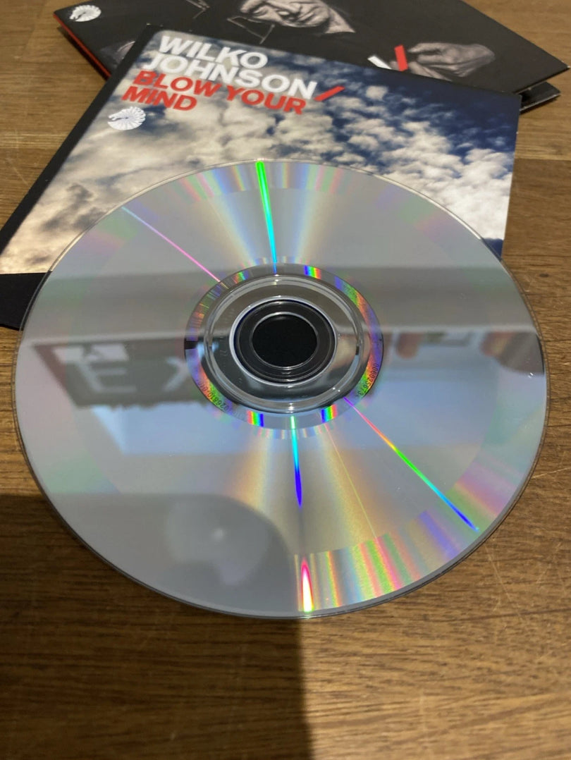 CD album with it's cardboard sleeve titled 'Wilko Johnson Blow Your Mind' in the background
